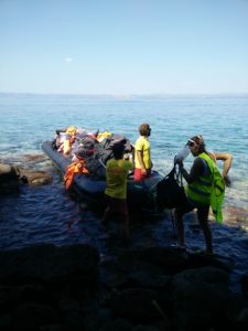 Kuvassa kumivene, jossa roskia, pääasiassa pelastusliivejä. Kuvassa kolme vapaaehtoista, jotka siivonneet rantaa.